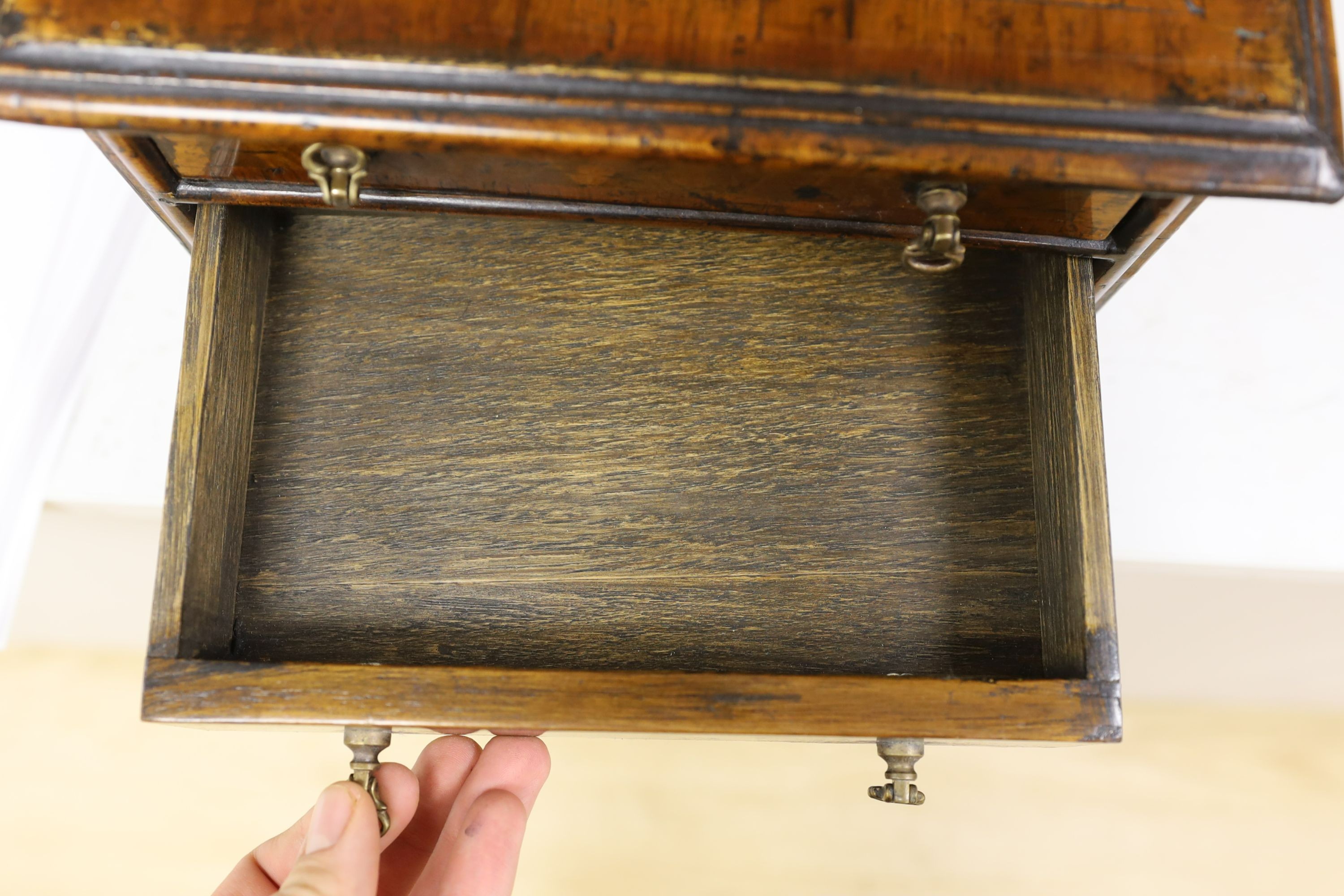 A cross banded walnut miniature chest of three drawers, 26cm wide